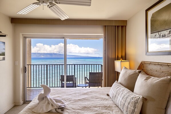 Relax on the large bed, overlooking the serene body of water from the balcony.