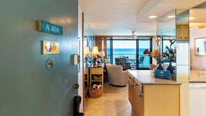 A modern hotel room with a balcony, a dining area, and a kitchen.