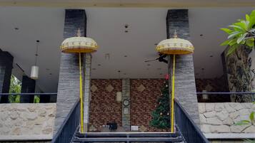 A hotel entrance with a brick facade, two ornate lamps, and a Christmas tree.