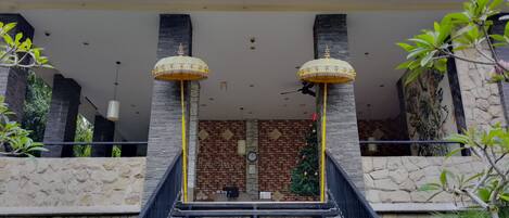 L’entrée d’un hôtel avec une façade en briques, deux lampadaires décoratifs et un sapin de Noël.