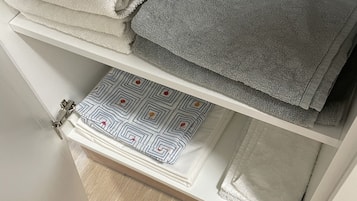 A storage unit with folded towels and a patterned pillow.