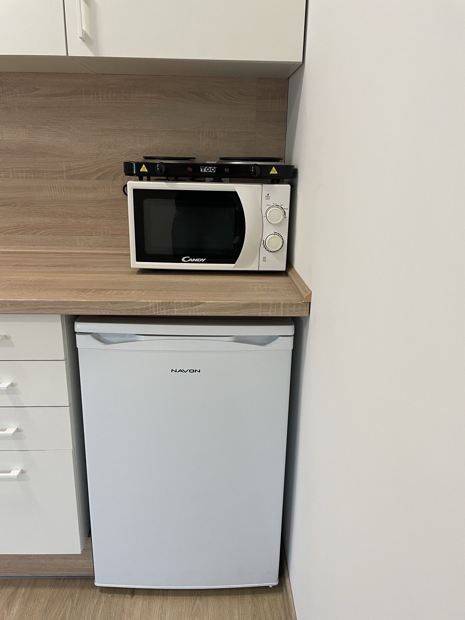 Une cuisine compacte avec un four à micro-ondes posé sur un plan de travail en bois et un lave-vaisselle en dessous.