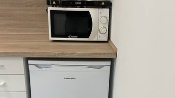 Une cuisine compacte avec un four à micro-ondes posé sur un plan de travail en bois et un lave-vaisselle en dessous.