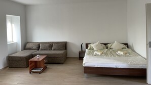 Un dormitorio con cama, sofá, mesita de noche y una pequeña mesa de madera.