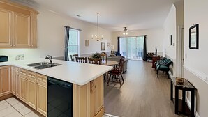 A spacious kitchen with a central island, a dining area with chairs, and a living room with a sofa and chairs. - Golf and Beach Getaway Relaxation at its Finest (Pawleys Island)