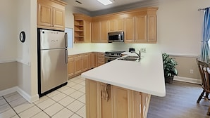 A kitchen with wooden cabinets, a stainless steel refrigerator, a microwave, a stove, and a sink. - Golf and Beach Getaway Relaxation at its Finest (Pawleys Island)