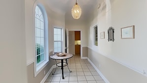 A hallway with a round table, a chandelier, and framed pictures on the walls. - Golf and Beach Getaway Relaxation at its Finest (Pawleys Island)