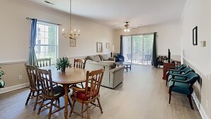 A spacious living room with a dining area, large windows, and a ceiling fan. - Golf and Beach Getaway Relaxation at its Finest (Pawleys Island)