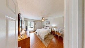 A bedroom with a bed, bedside tables, a nightstand, a ceiling fan, and a window. - Heron Marsh Hideaway Split Level Villa (Pawleys Island)