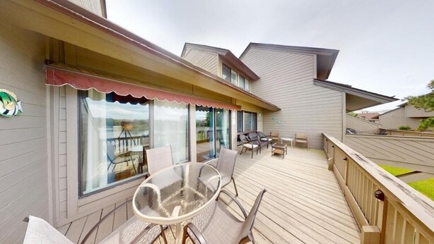 A modern house with a wooden deck, large windows, and outdoor furniture. - Heron Marsh Hideaway Split Level Villa (Pawleys Island)