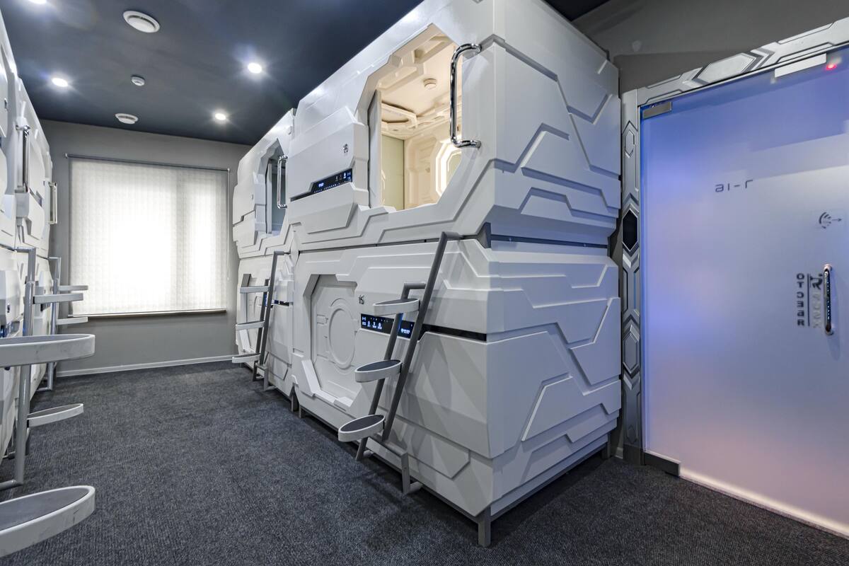 Une pièce futuriste dotée d’un grand motif géométrique blanc, d’un panneau de contrôle et d’une porte portant l’inscription « air-r ».