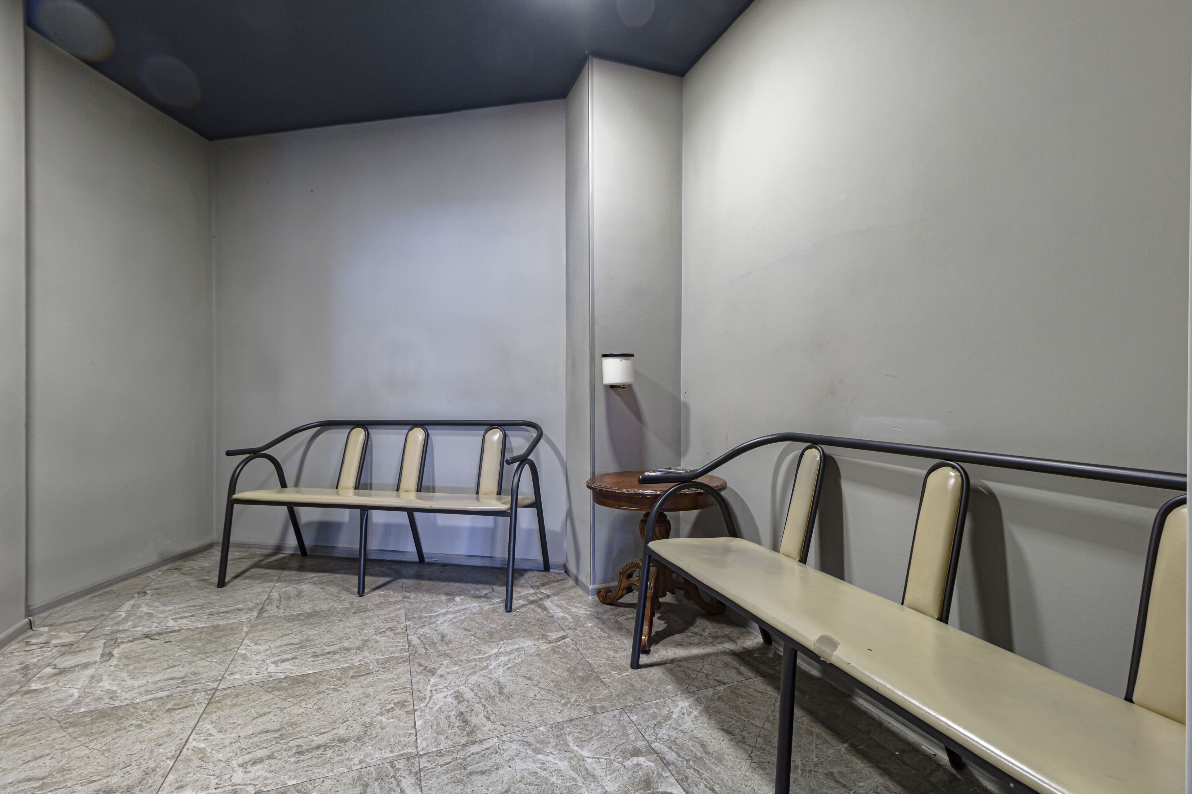 Un espace d’attente avec un banc et une table, une lampe et un sol carrelé.