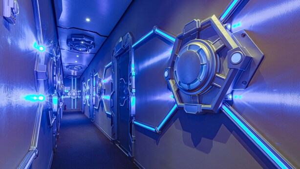 Een futuristische gang met metalen wanden en blauwe lichtaccenten.