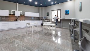 Een moderne keuken met witte kastjes, een roestvrijstalen aanrecht en een betegelde vloer.
