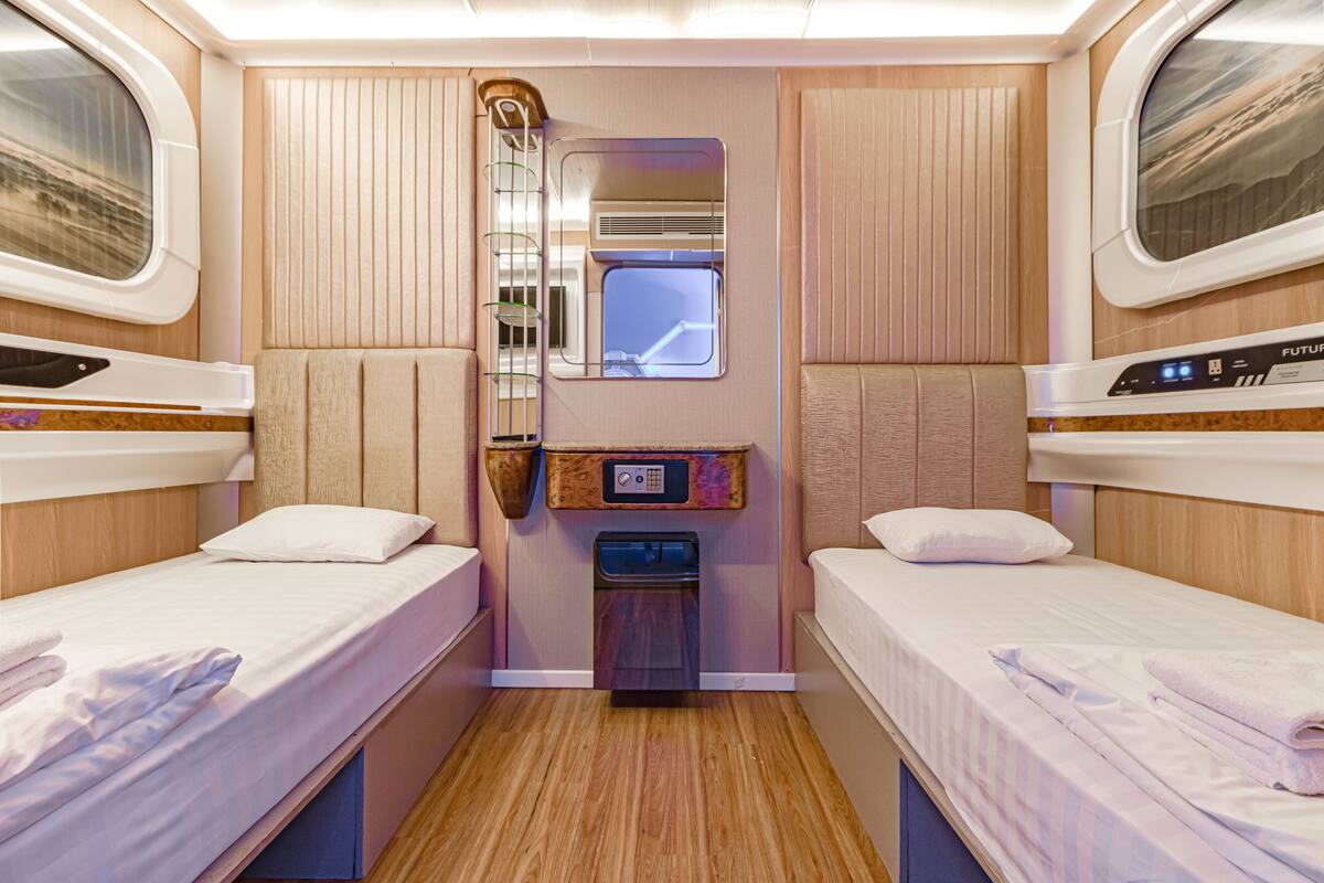 Une cabine compacte et bien éclairée, équipée de deux lits simples, d’une petite kitchenette et d’une fenêtre donnant sur l’extérieur.