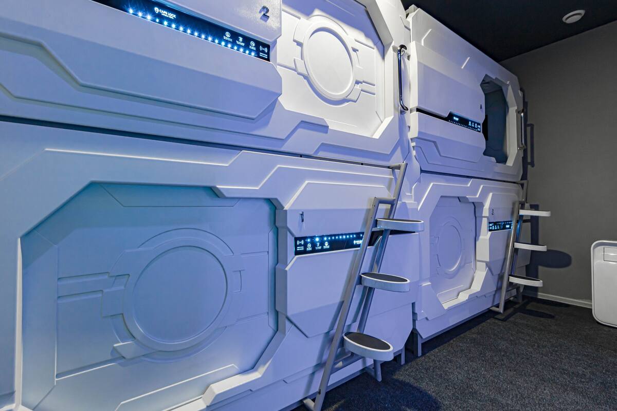 Une pièce contenant une grande machine au design futuriste, qui pourrait être un sauna ou un hammam, avec une échelle permettant d’y accéder.