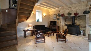 Una sala de estar acogedora con chimenea, una escalera de madera y una pared de piedra.