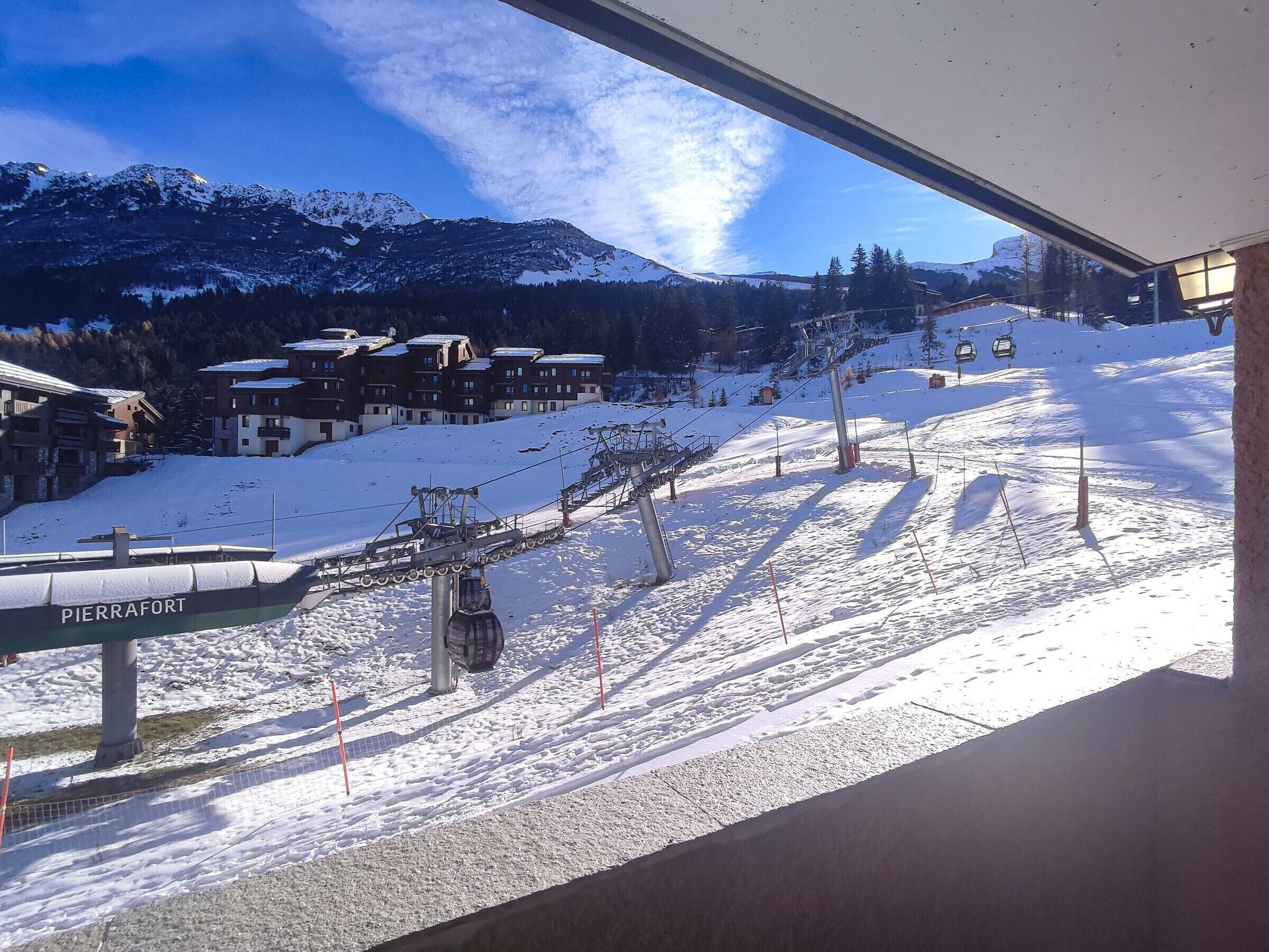 A ski lift with 'PIERRAFORT' signage, a snow-covered slope, and buildings in the background.
