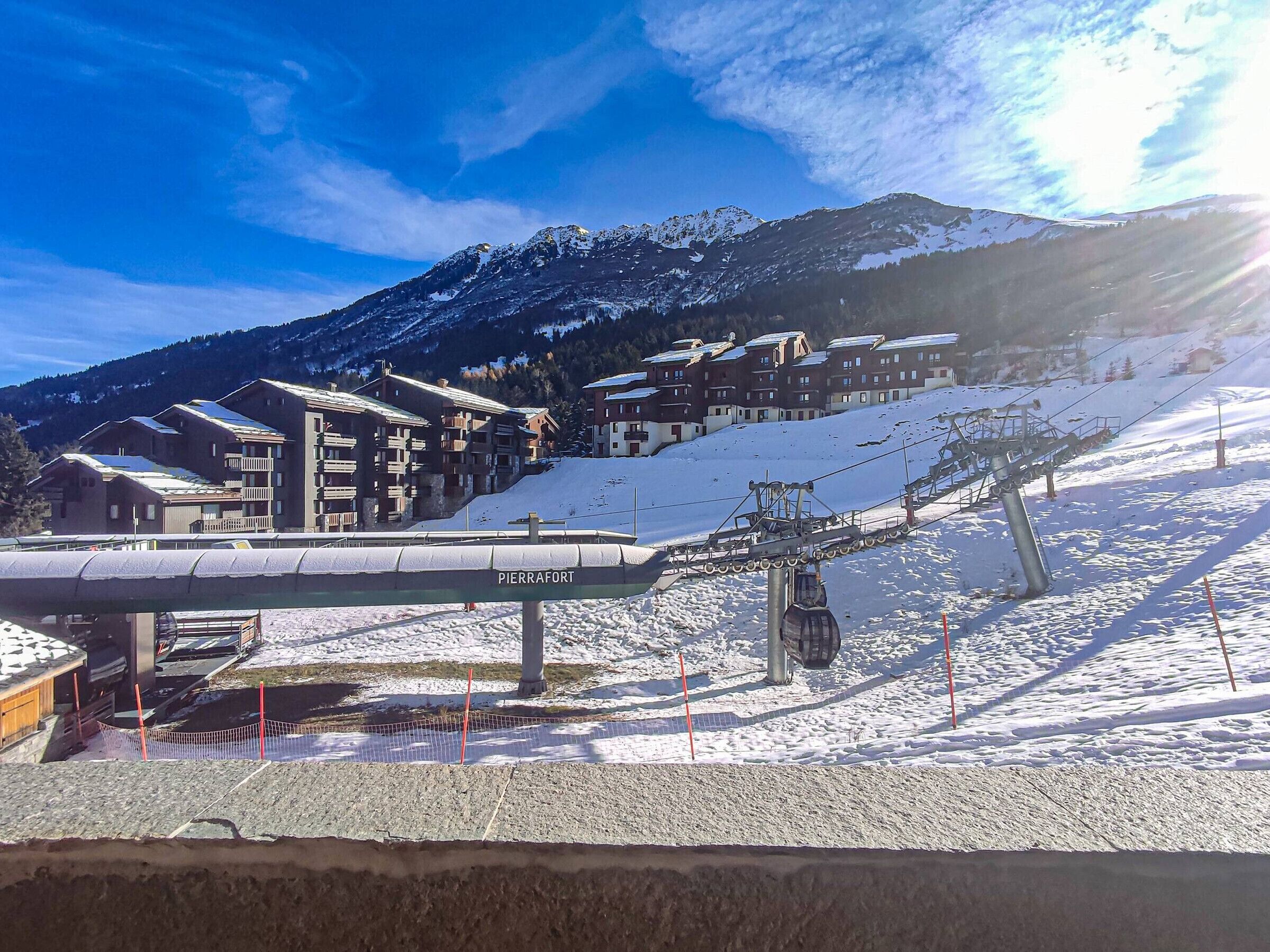 A ski resort with a cable car system, snow-covered slopes, and a mountain backdrop.