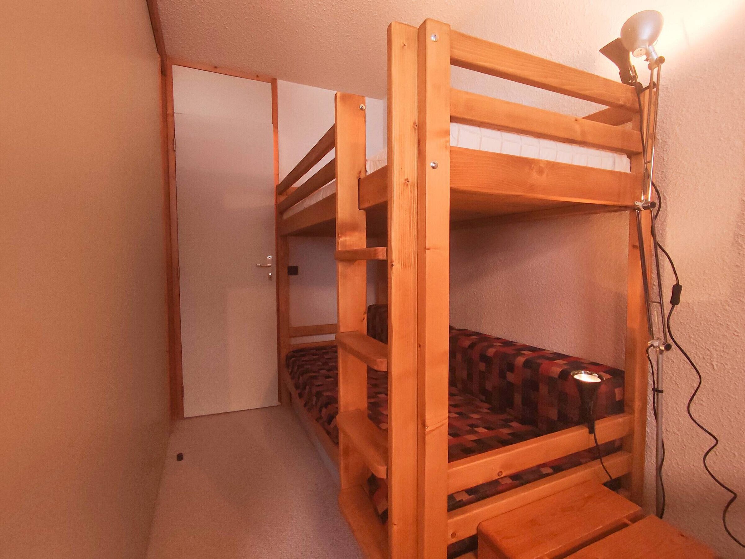 A bunk bed with a headboard, a bedside lamp, and a door in the background.
