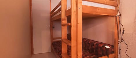 A bunk bed with a headboard, a bedside lamp, and a door in the background.