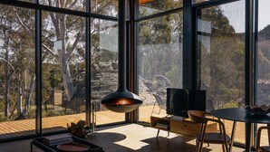 A modern interior with large windows, a fireplace, and a dining area. - Wambal Cabin - luxury in the wilderness (Coxs Creek)