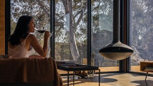 A modern interior with a large window, a hanging light fixture, and a cozy seating area. - Wambal Cabin - luxury in the wilderness (Coxs Creek)