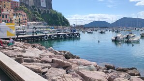 A marina with boats docked, a castle in the background, and a rocky shoreline.
