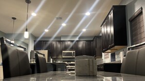 Una cucina moderna con mobili scuri, un forno a microonde in acciaio inossidabile e un piano di lavoro in marmo.