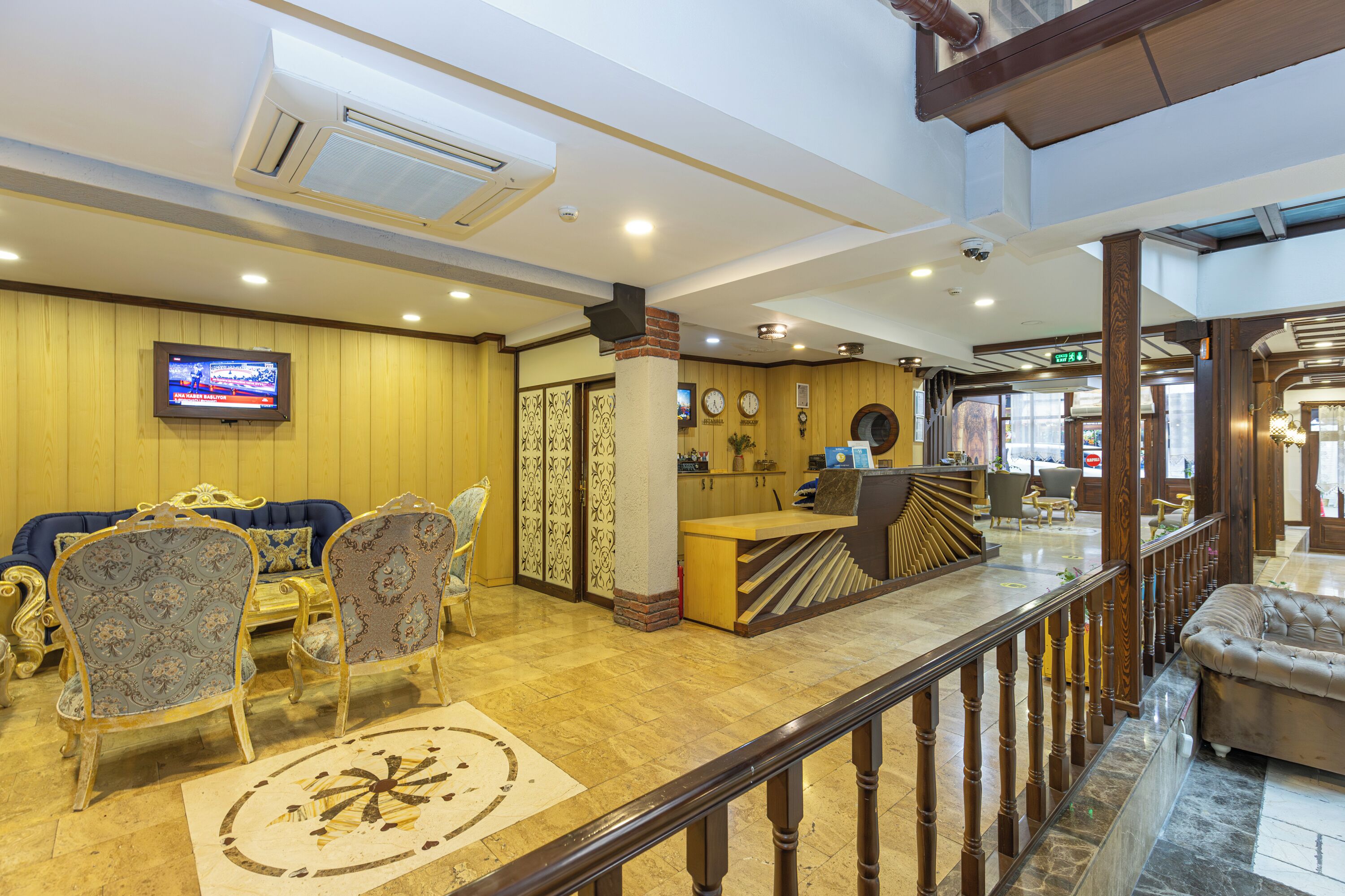 A hotel lobby with a reception desk, seating area, and a television screen.