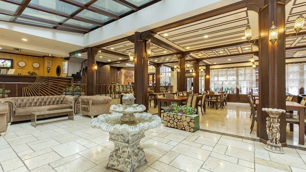 A spacious lobby with a high ceiling, wooden beams, and a central fountain.