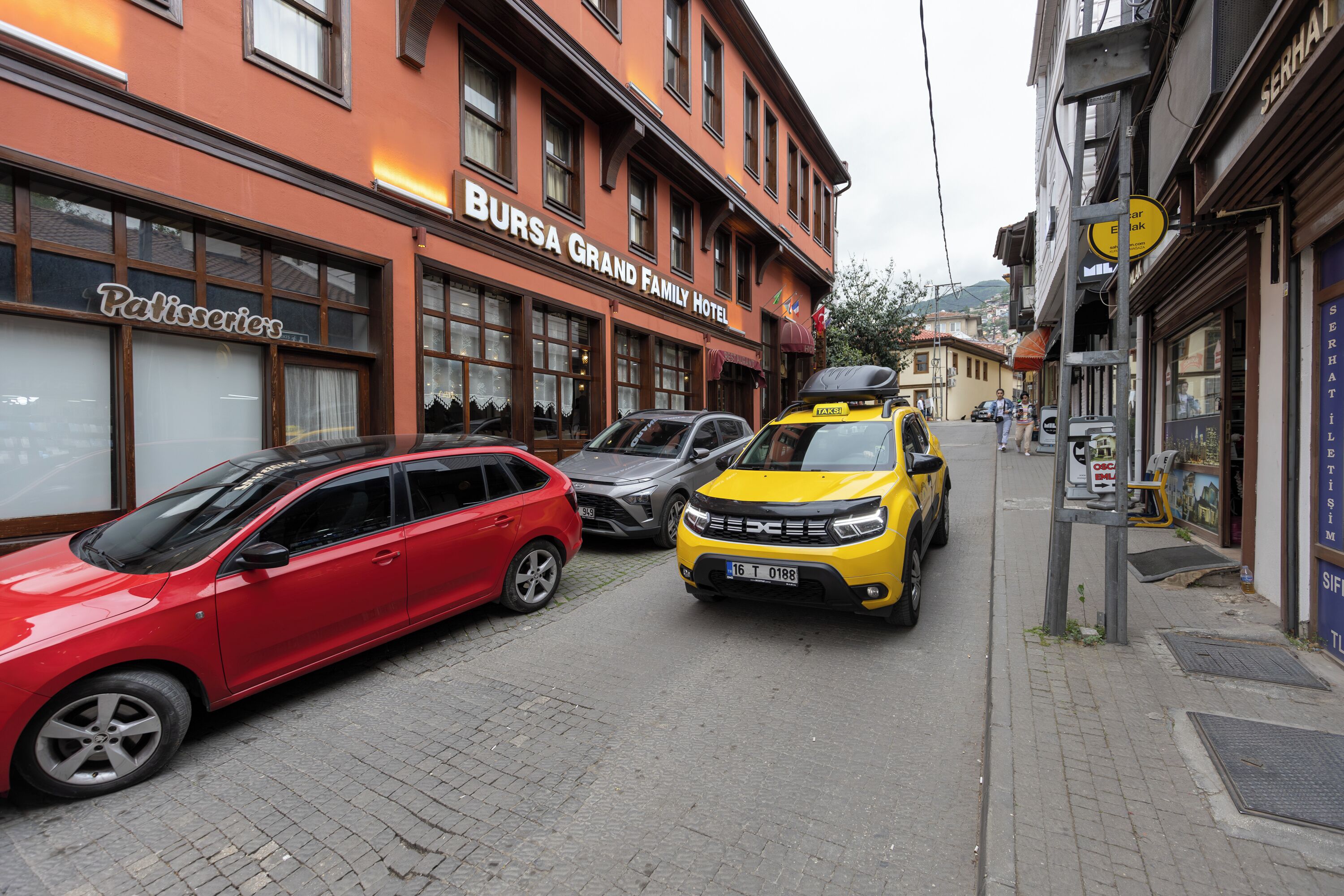 A street view with a building labeled "BURSA GRAND FAMILY HOTEL" and a "Patisserie" sign.