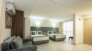A hotel room with two beds, a sofa, a small table, and a chair.
