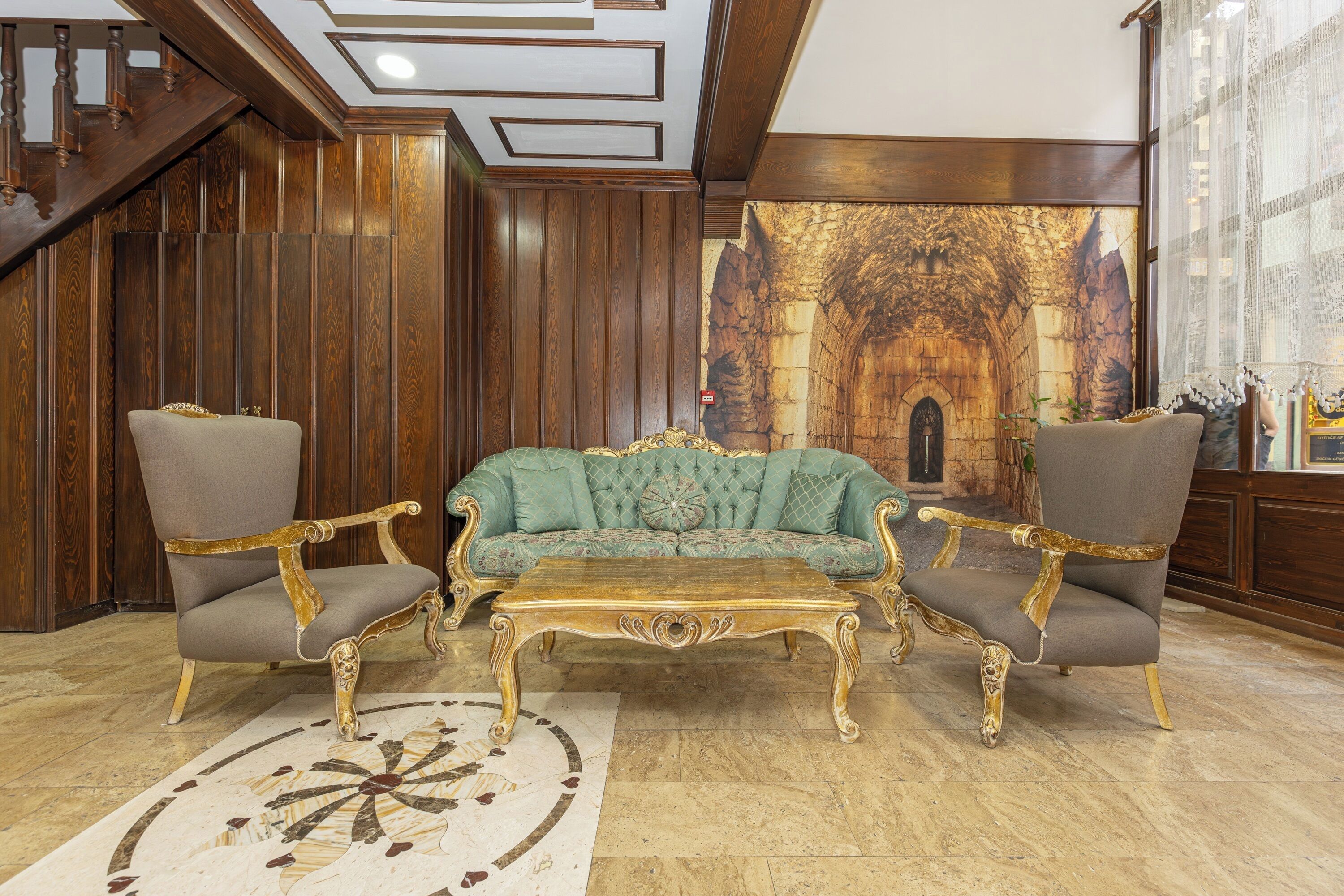 A grand room with a large, ornate sofa and matching armchairs, a decorative coffee table, and a patterned rug.