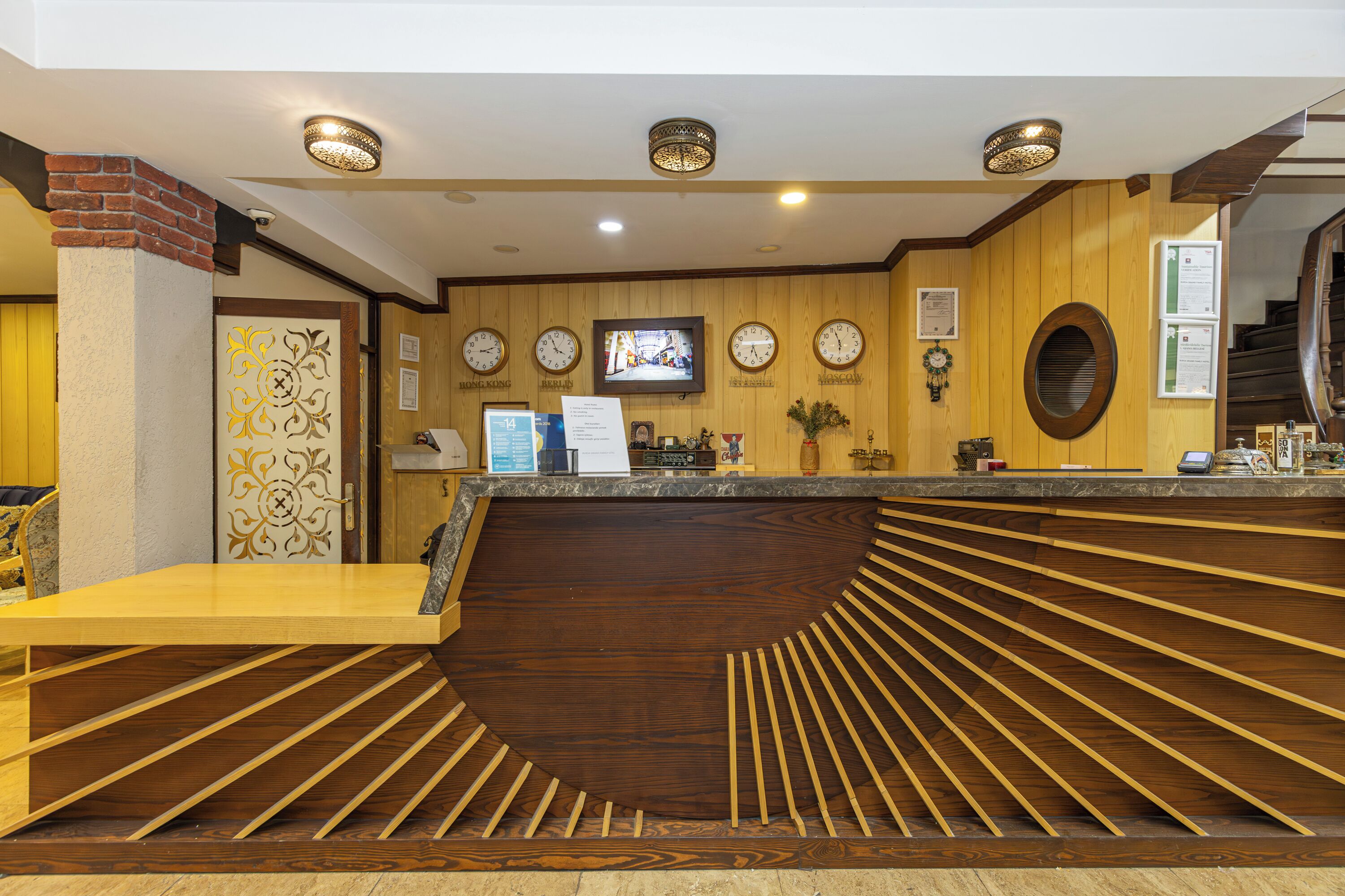 A reception area with a wooden reception desk, a television mounted on the wall, and a clock.