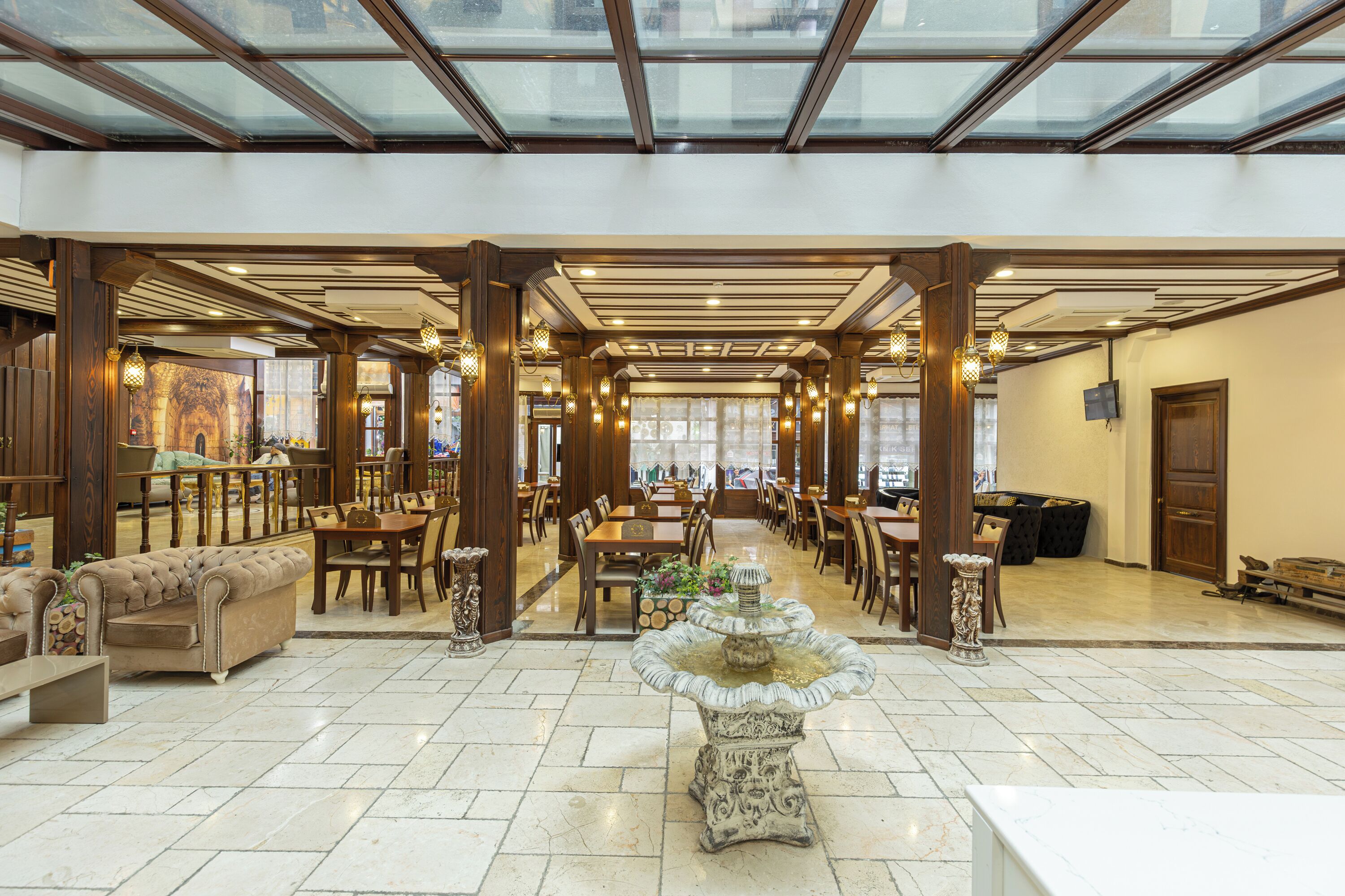 A spacious hotel lobby with a high ceiling, large windows, and a central fountain.