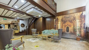 A lobby with a grand staircase, a plush seating area, and a large mural depicting an ancient stone archway.