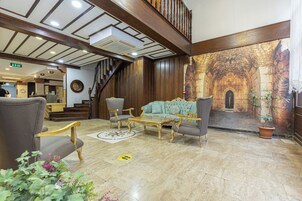 Un vestíbulo con una imponente escalera, un espacio de descanso con sillones cómodos y un gran mural que representa un antiguo arco de piedra.