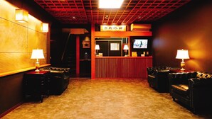 A lobby with a reception desk, two armchairs, a television, and a patterned carpet. - Nara Ryokan (Nara)