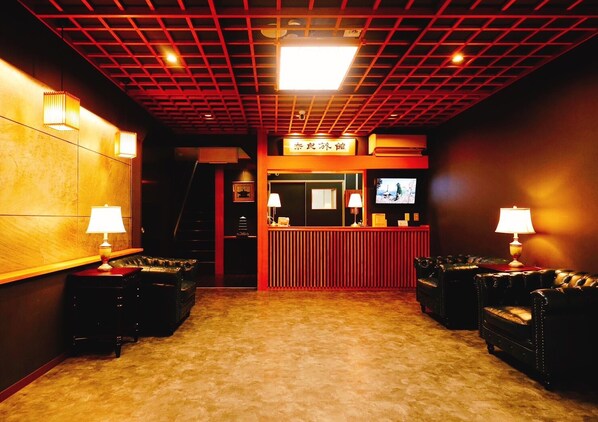 A lobby with a reception desk, two armchairs, a television, and a patterned carpet. - Nara Ryokan (Nara)