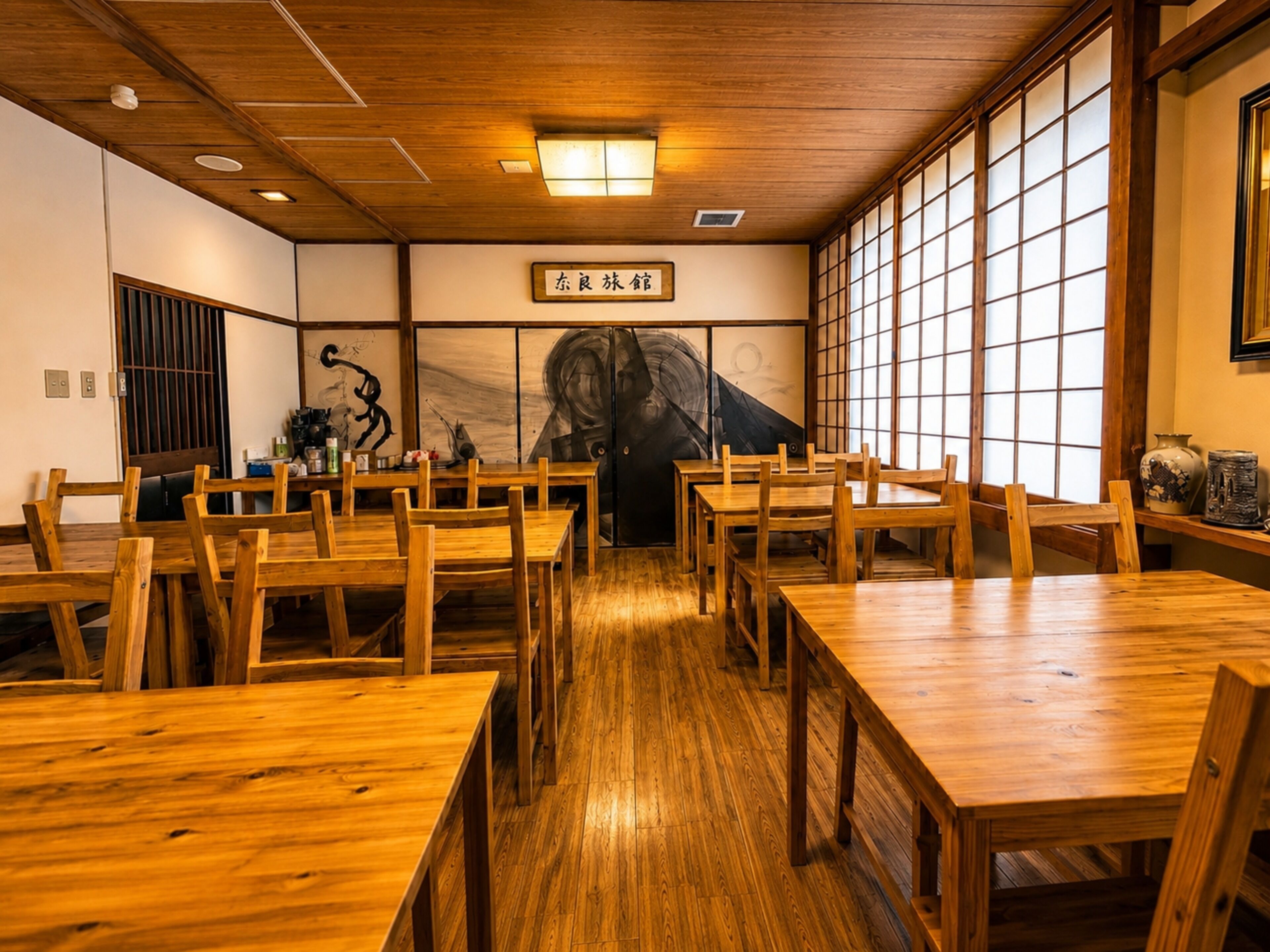 A traditional Japanese restaurant interior with wooden tables and chairs, a tatami mat floor, and a large shoji screen door.
