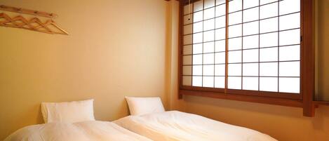 A bedroom with a bed, a window with a grid pattern, and a wooden ceiling.