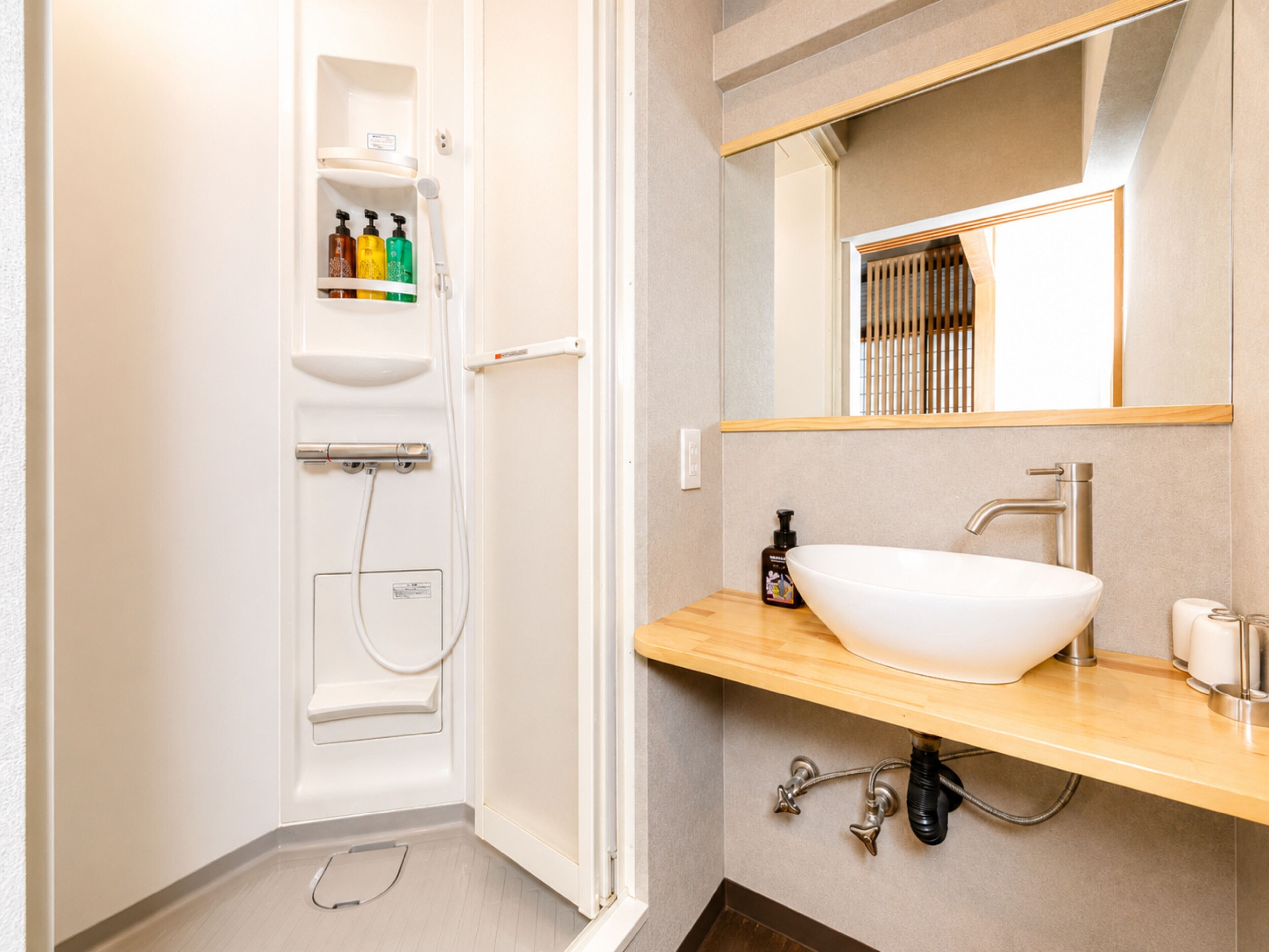 A modern bathroom with a white sink, mirror, and shower enclosure.