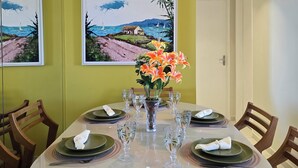 A dining area with a round table set for six, surrounded by wooden chairs. - Vista Mar na Pajuçara: Amplo 2Q p/ 6 Pessoas (Maceió)