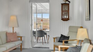 Une pièce confortable avec un canapé, un fauteuil, une table avec une lampe et une horloge au mur.