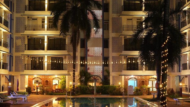 A multi-story hotel with balconies, a pool area, and outdoor seating. - Palmarinha De Goa unit of GKP Real Estat (Calangute)