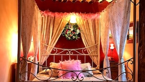 A four-poster canopy bed with floral bedding and a red headboard. - Room in a beautiful rural house from the 17th century in Cuenca. (Valeria)