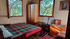 A room with a bed, a desk, a guitar, and a wardrobe.