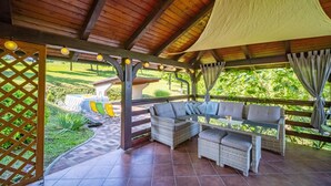 Un espace extérieur aménagé, abrité et doté de mobilier en osier, offrant une vue sur un terrain de golf.