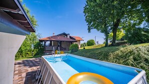Une piscine avec un flotteur, un patio couvert et une maison en arrière-plan.